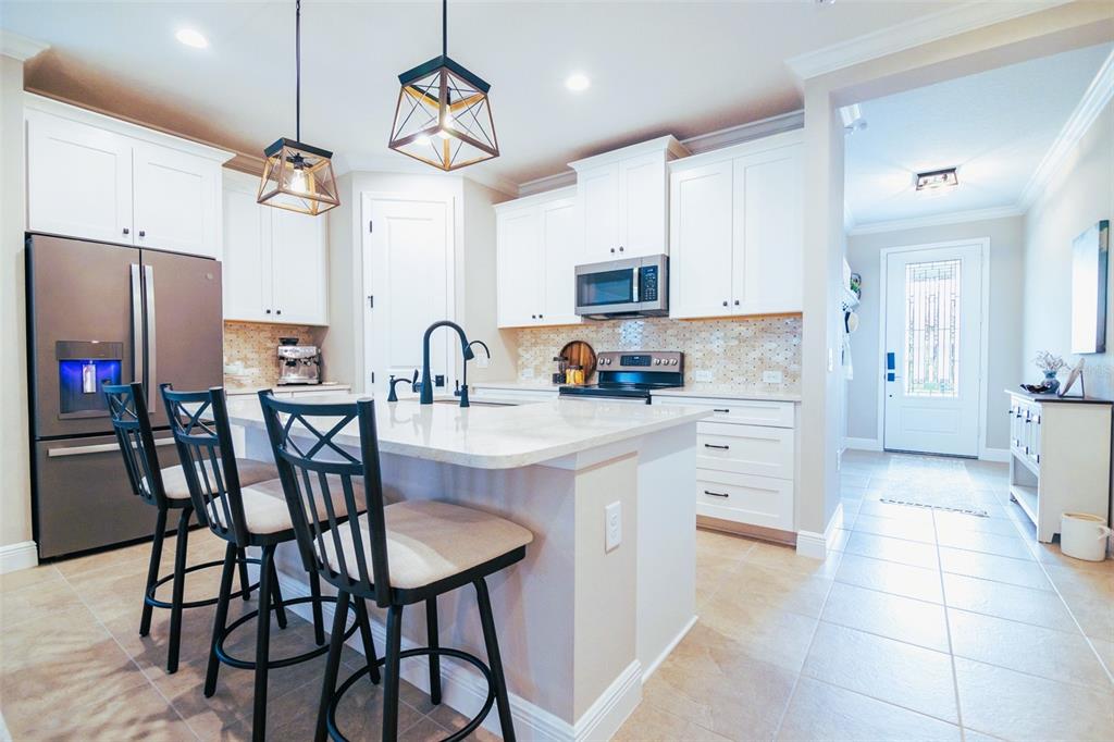 13153 Steinhatchee Loop Venice, FL 34293 - Photo 8 of 33 a kitchen with stainless steel appliances a table chairs microwave and refrigerator