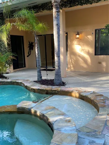 a view of a house with backyard sitting area and swimming pool