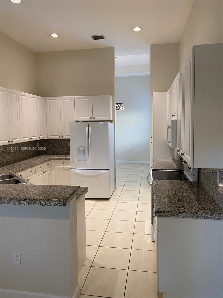 7564 Southwest 190th Street, Unit 7564 Cutler Bay, FL 33157 - Photo 6 of 22 a kitchen with granite countertop a sink and a stove top oven