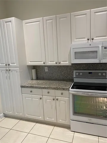 a kitchen with white cabinets and appliances