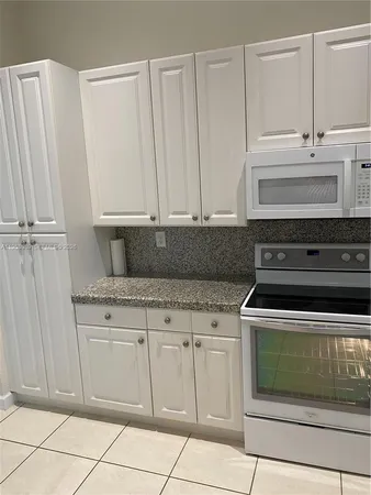 a kitchen with white cabinets and appliances