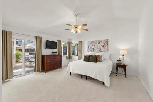 a bedroom with a bed chandelier and a flat tv screen on dresser