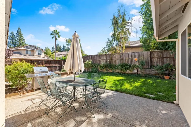 a view of a chair and table in backyard of the house