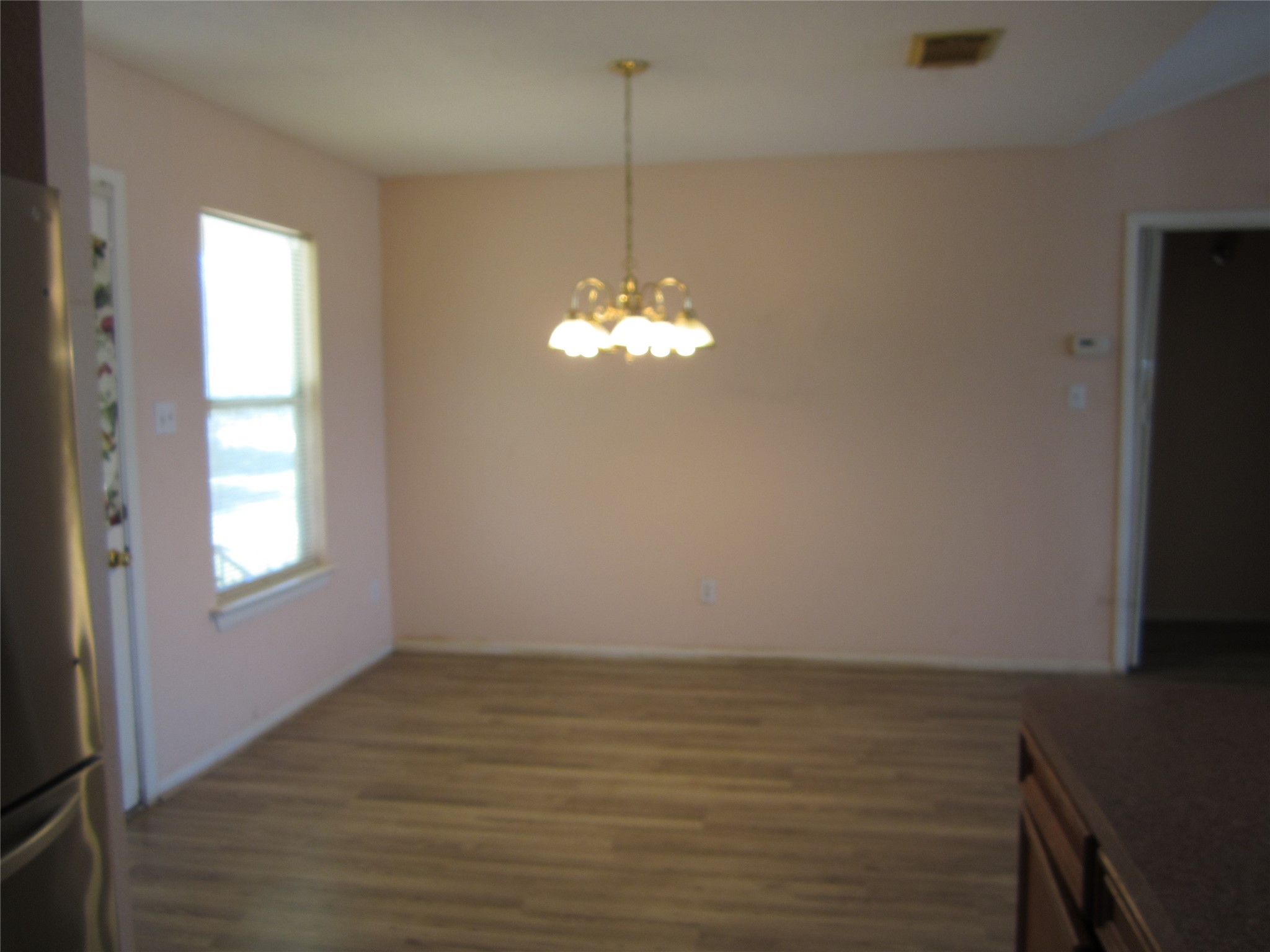 20697 Pierceall Road Hempstead, TX 77445 - Photo 13 of 35 This photo features a dining area with light wood flooring, a central hanging light fixture, and a window providing natural light. The space is adjacent to the kitchen.
