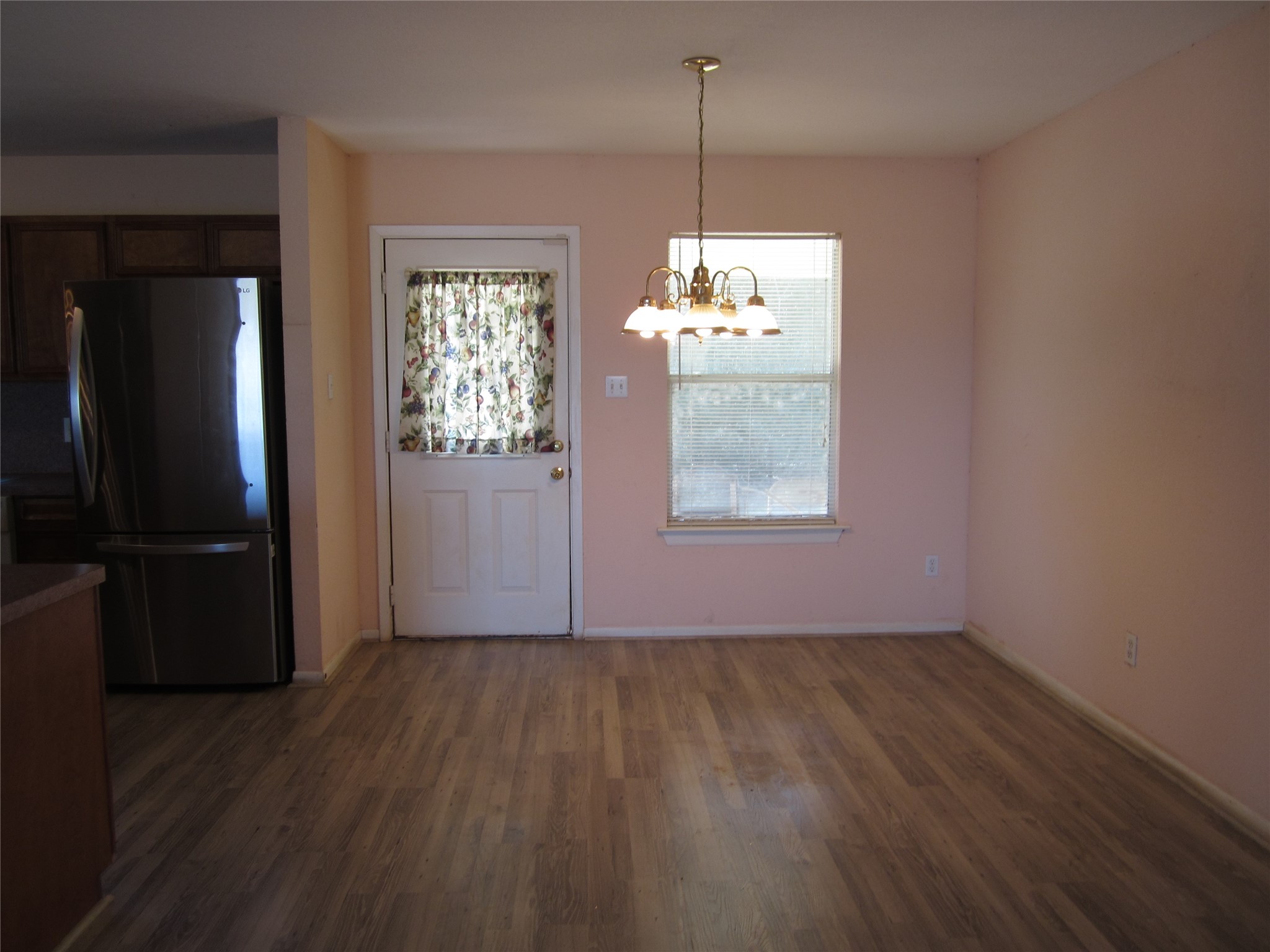 20697 Pierceall Road Hempstead, TX 77445 - Photo 14 of 35 This photo shows a dining area with laminate flooring. It features a hanging light fixture, a window, and a door that leads out to the covered back porch.