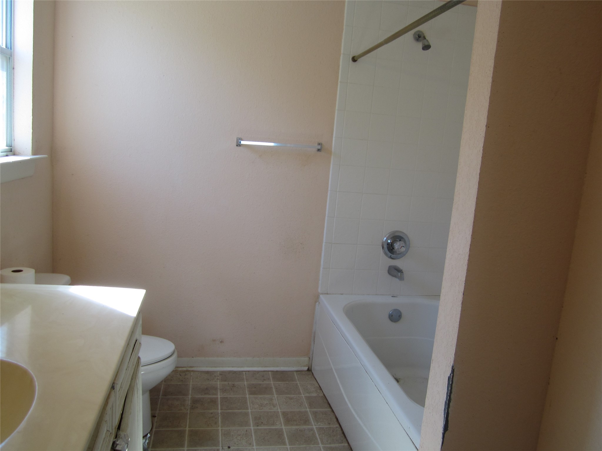 20697 Pierceall Road Hempstead, TX 77445 - Photo 19 of 35 Primary bathroom featuring a bathtub with shower, single sink vanity, and a toilet. Natural light enters through the window, illuminating the tiled floor.