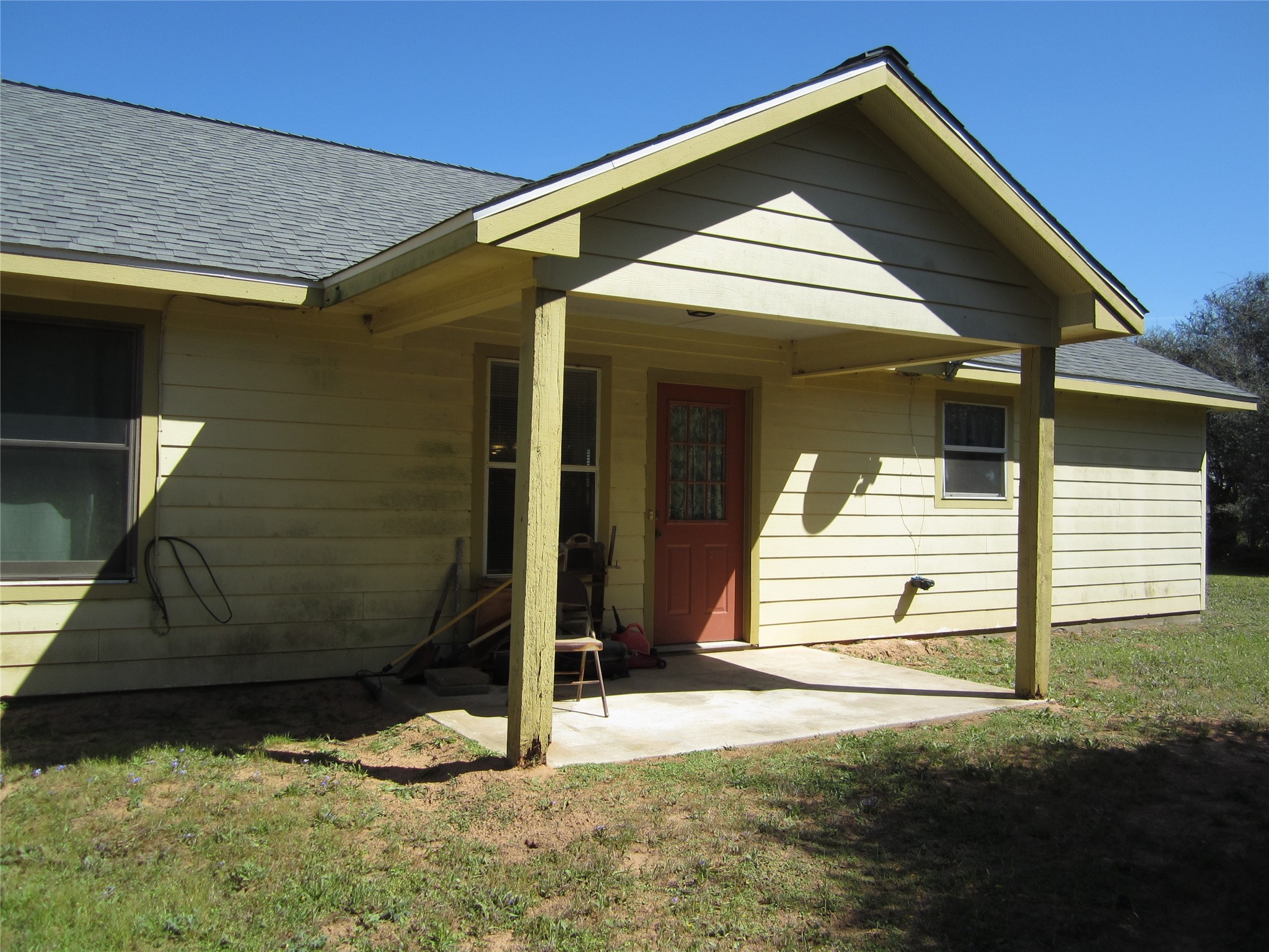 20697 Pierceall Road Hempstead, TX 77445 - Photo 32 of 35 This photo shows the back of a single-story house . There's a small covered patio area with a door leading into the dining room/kitchen area.