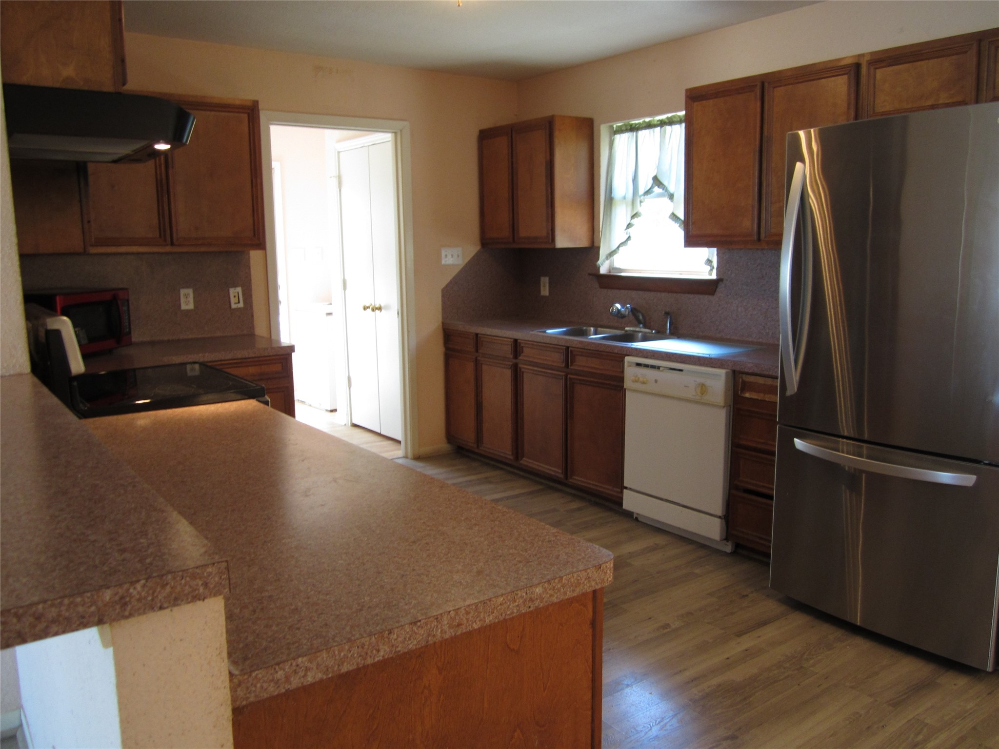 20697 Pierceall Road Hempstead, TX 77445 - Photo 4 of 35 This kitchen features warm wood cabinetry, a spacious countertop, stainless steel refrigerator, and a dishwasher. Natural light enters through a small window, complementing the functional layout. Refrigerator conveys with sale.