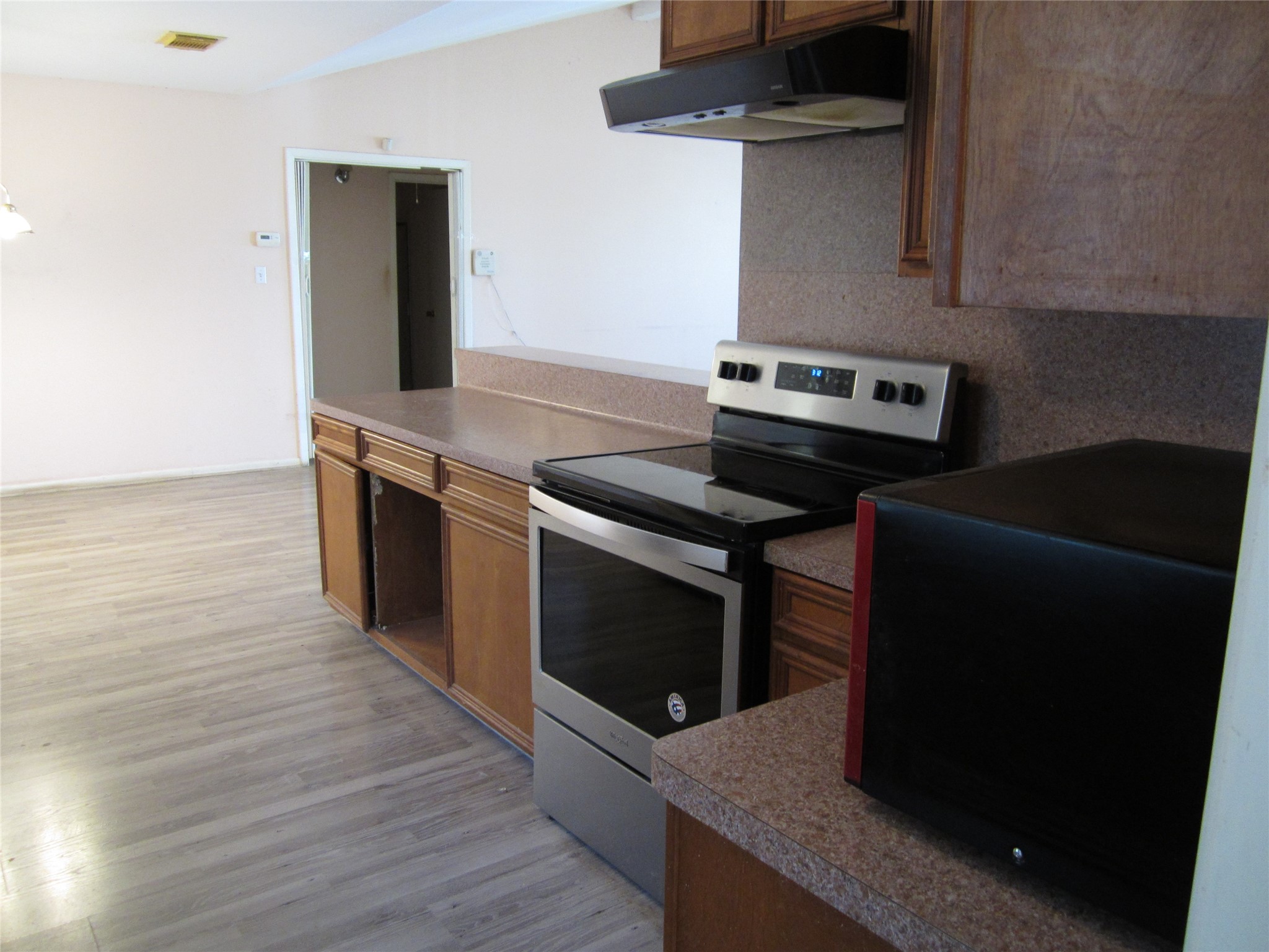 20697 Pierceall Road Hempstead, TX 77445 - Photo 6 of 35 This photo shows a kitchen with wooden cabinets, a stainless steel oven, and laminate flooring. The space is open and leads into the dining room.