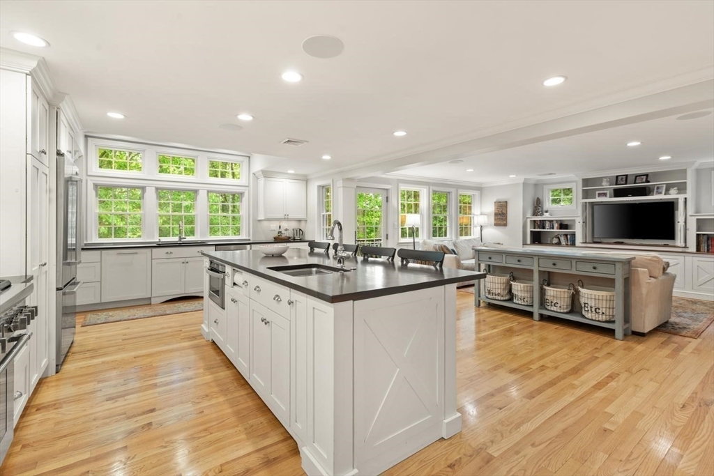 105 Thornberry Road Winchester, MA 01890 - Photo 5 of 35 a large kitchen with stainless steel appliances a large counter top a stove a chimney a sink and living room view