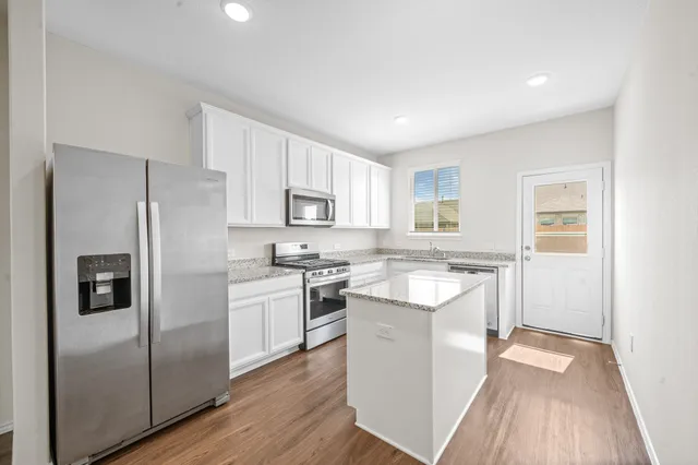 a kitchen with a refrigerator a sink and dishwasher with wooden floor