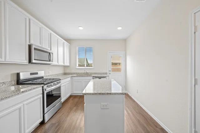 a kitchen with granite countertop white cabinets and white appliances