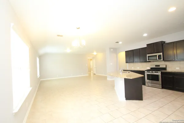 a large kitchen with kitchen island granite countertop a sink and a stove top oven
