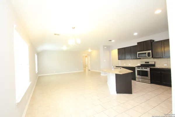 a large kitchen with stainless steel appliances kitchen island granite countertop a refrigerator a sink a stove top oven and a dishwasher