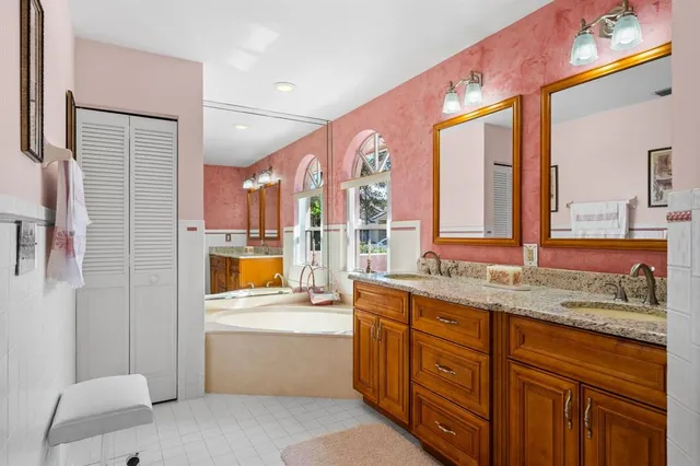 a bathroom with a granite countertop double vanity sink a mirror and a shower