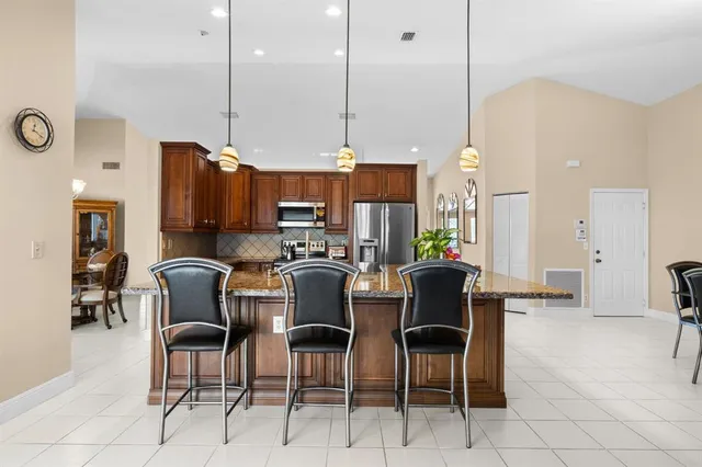 a kitchen island with stainless steel appliances a stove a sink a oven a dining table and chairs
