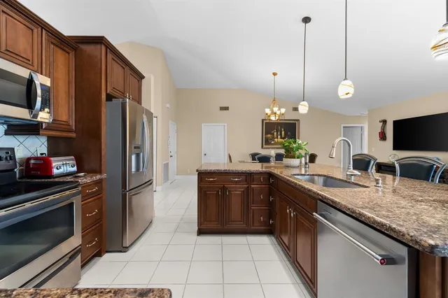 a kitchen with stainless steel appliances granite countertop a sink a stove top oven and refrigerator