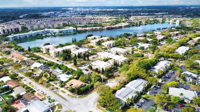 an aerial view of city and lake with trees