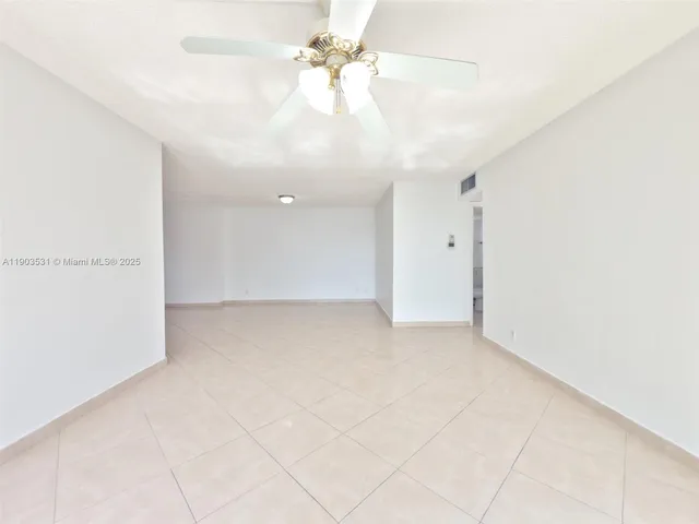an empty room with chandelier fan and windows