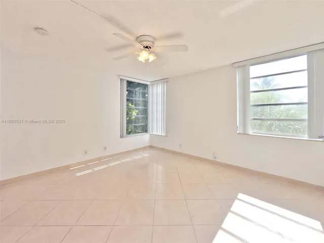 an empty room with chandelier fan and windows