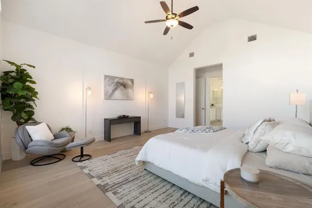 a spacious bedroom with a bed a couch and potted plant