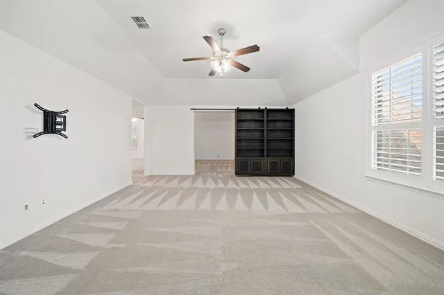 an empty room with wooden floor and ceiling fan