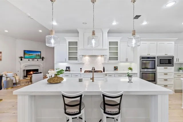 a kitchen with stainless steel appliances a sink a stove a refrigerator cabinets and chairs