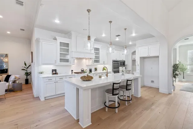 a kitchen with a sink a stove a refrigerator and white cabinets with wooden floor