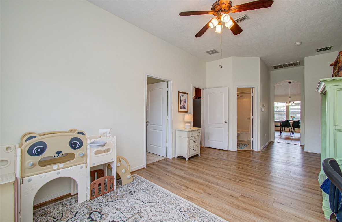 20007 Alcea Court Spring, TX 77379 - Photo 14 of 43 This bright room features wood flooring, a ceiling fan, and a playful children's playset. It connects seamlessly to additional living spaces and has access to a bathroom, making it versatile for various uses.
