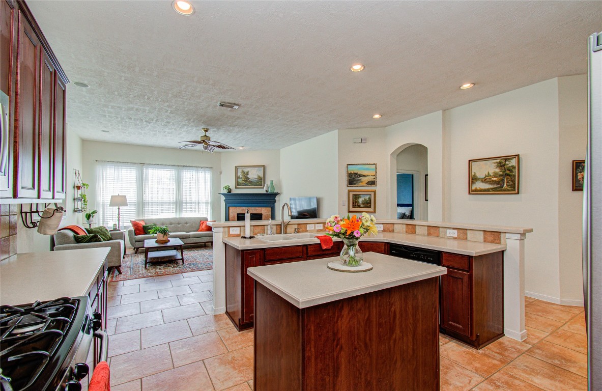 20007 Alcea Court Spring, TX 77379 - Photo 18 of 43 This inviting home features an open concept layout with a spacious kitchen island flowing into a cozy living area. Large windows provide abundant natural light, complementing the warm tile flooring and elegant cabinetry. Perfect for entertaining or family gatherings.