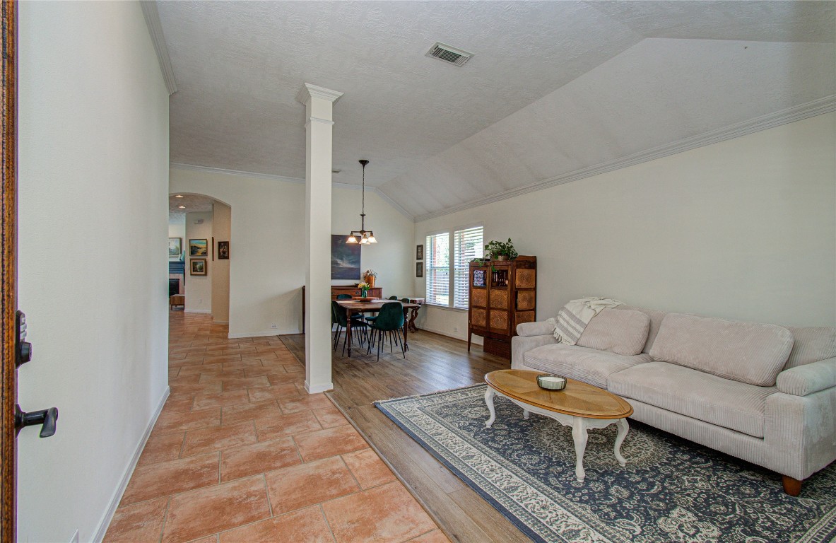 20007 Alcea Court Spring, TX 77379 - Photo 5 of 43 This photo showcases a welcoming open-concept living and dining area with a cozy beige sofa, a classic rug, and warm wood and tile flooring. Natural light fills the space through large windows, highlighting the tasteful decor and bright, airy feel.
