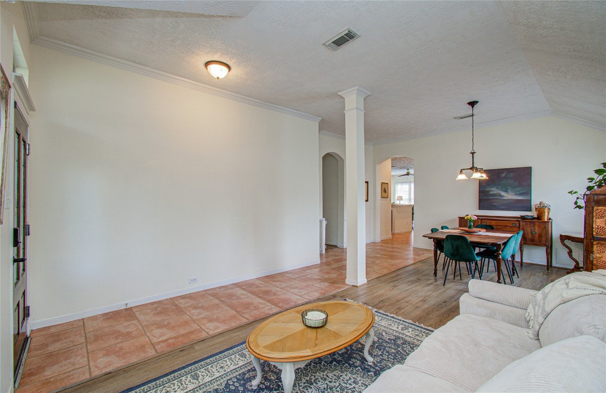 20007 Alcea Court Spring, TX 77379 - Photo 7 of 43 This inviting front living and dining area features a mix of tile and wood flooring, neutral walls, and a high ceiling with a column accent. A cozy seating area complements the open layout, leading to a well-lit dining space.