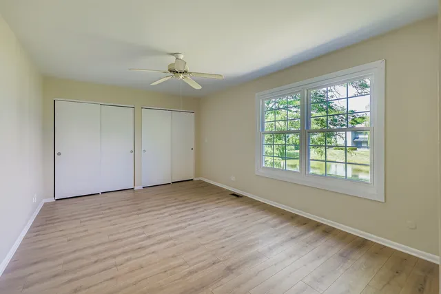 a view of an empty room with a window and wooden floor