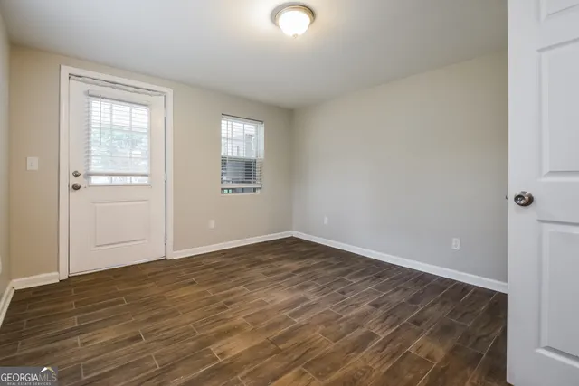 a view of an empty room with wooden floor and a window