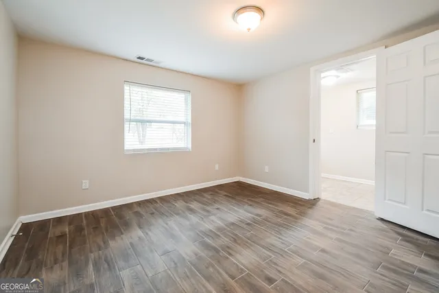 an empty room with wooden floor and windows