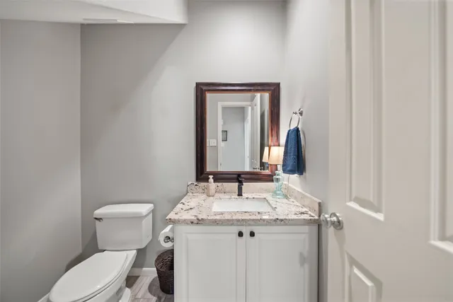 a bathroom with a granite countertop sink mirror vanity and toilet