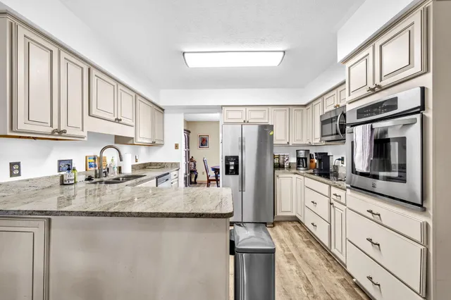 a kitchen with stainless steel appliances kitchen island granite countertop a refrigerator stove top oven and sink