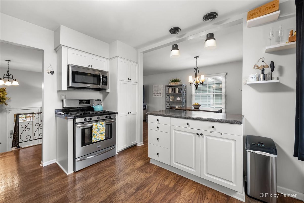647 North Ridgemoor Avenue Mundelein, IL 60060 - Photo 11 of 39 a kitchen with stainless steel appliances white cabinets a sink a stove a microwave and wooden floors