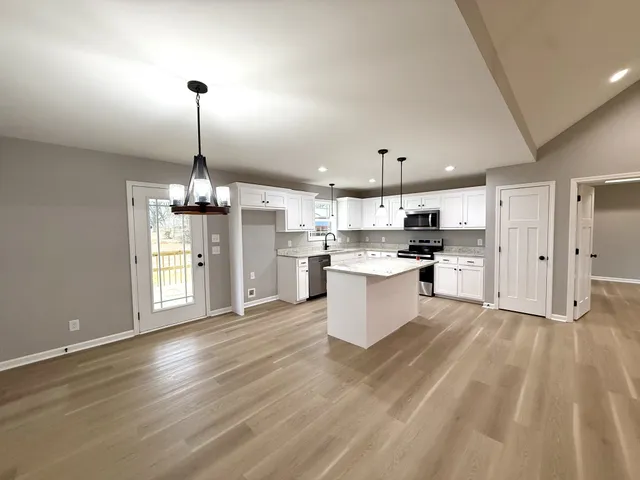 a view of kitchen and empty room with wooden floor