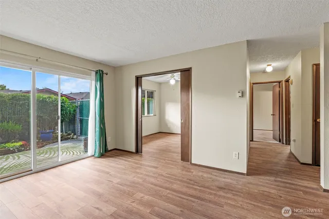 a view of an empty room with wooden floor and a window