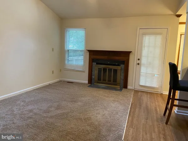 an empty room with wooden floor fireplace and windows