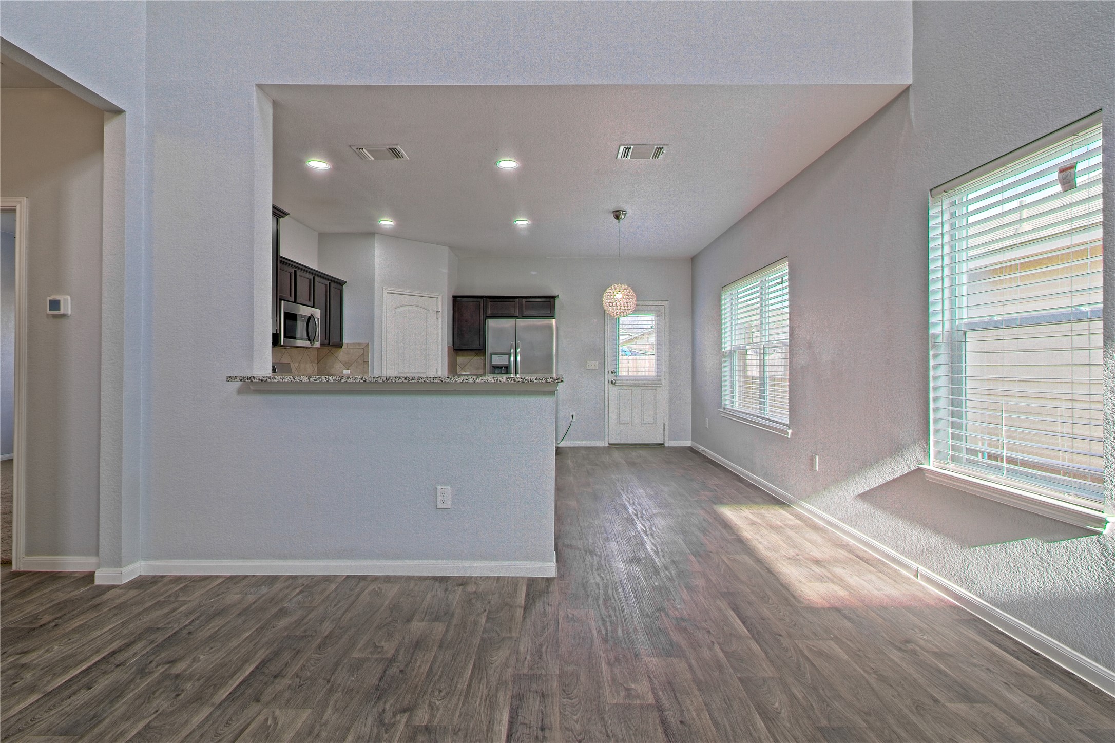 3408 Tilmon Ln. Austin, TX 78725 - Photo 12 of 35 Kitchen featuring dark wood-type flooring, stainless steel appliances, dark wood finish cabinets, hanging light fixtures, and a peninsula