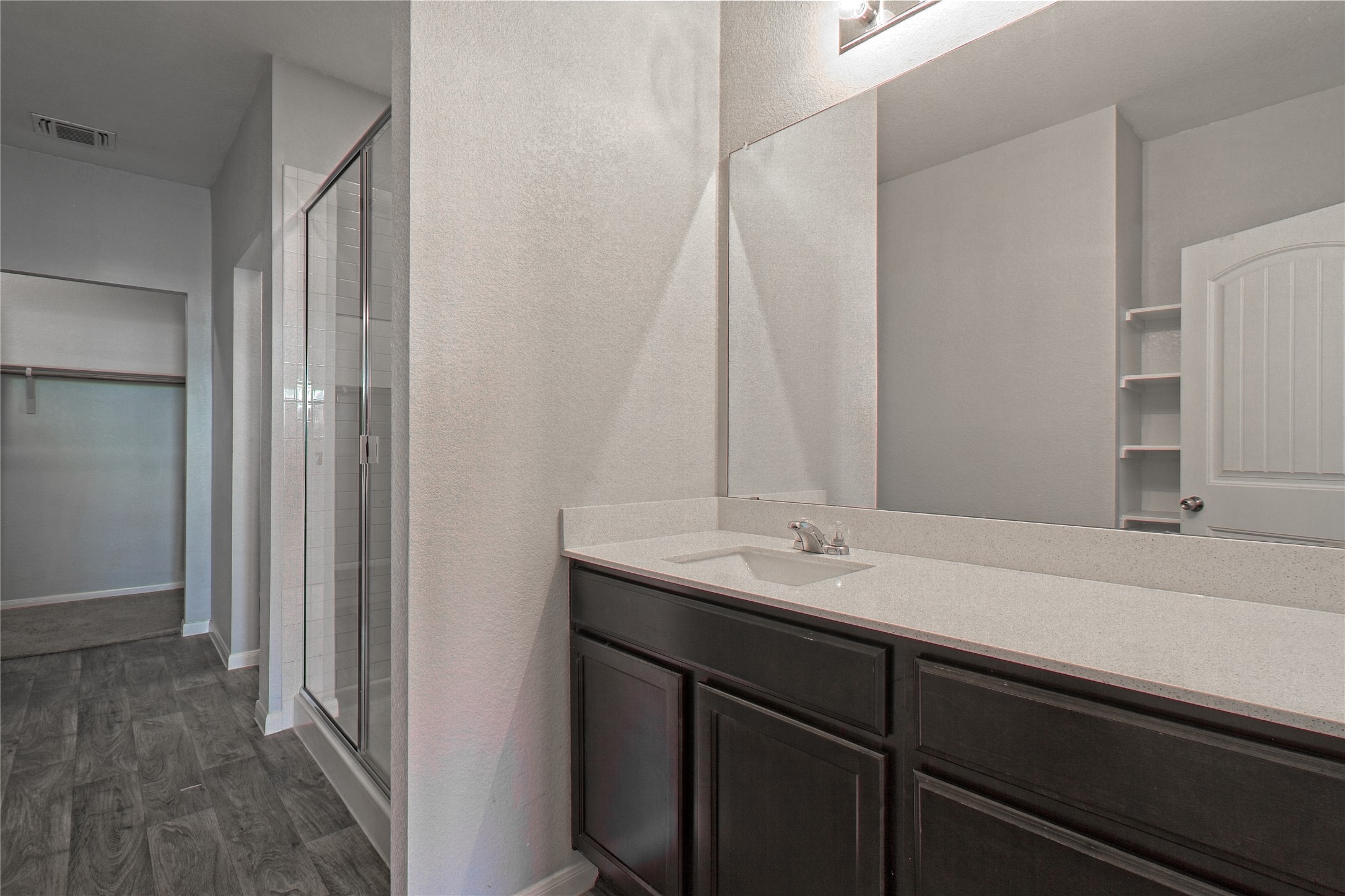 3408 Tilmon Ln. Austin, TX 78725 - Photo 21 of 35 Full bathroom featuring dark wood-style flooring, a stall shower, vanity, a spacious closet, and a textured wall