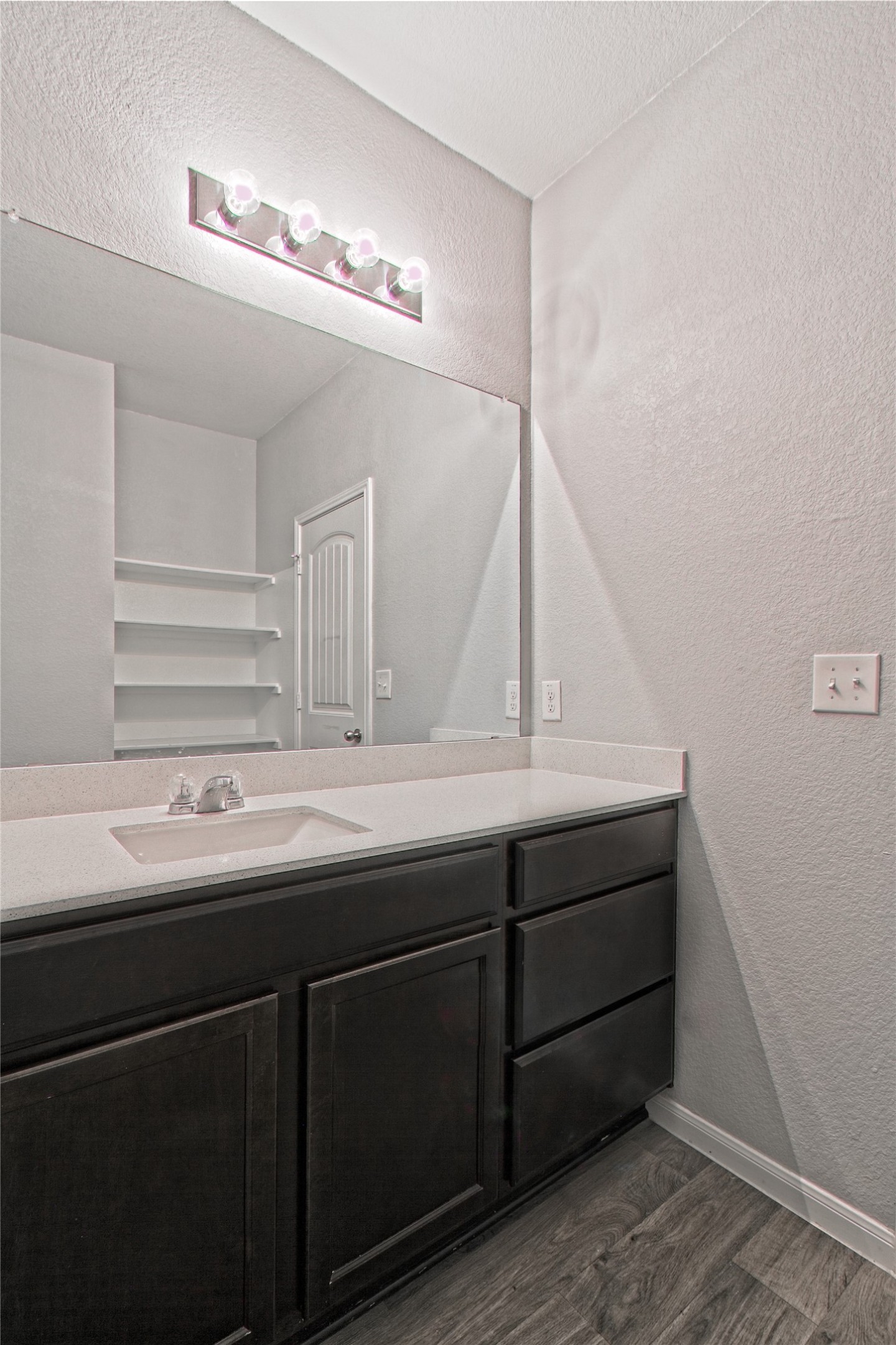 3408 Tilmon Ln. Austin, TX 78725 - Photo 22 of 35 Bathroom featuring a textured wall, vanity, dark wood-style flooring, and a textured ceiling