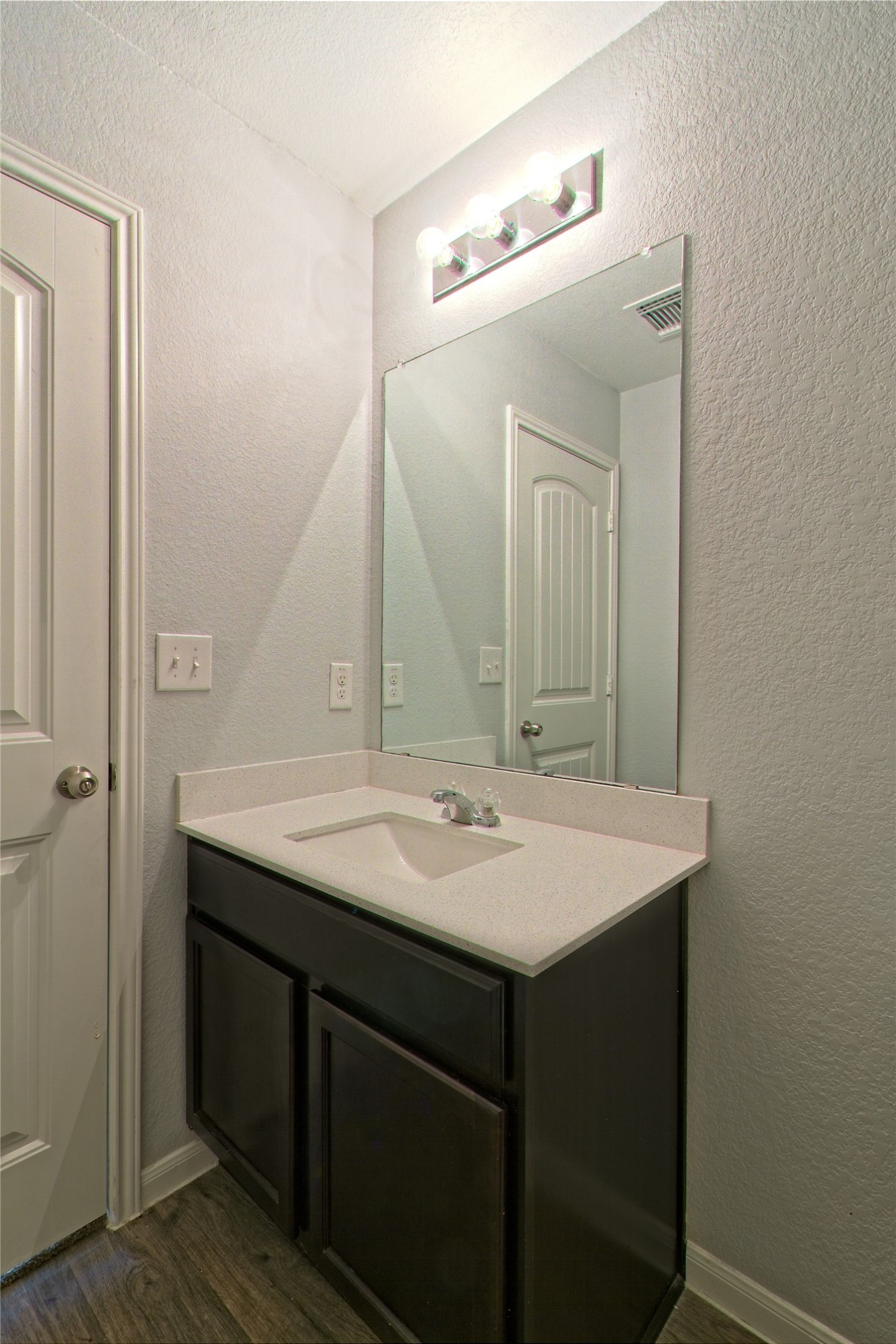 3408 Tilmon Ln. Austin, TX 78725 - Photo 27 of 35 Bathroom featuring a textured wall, vanity, and dark wood finished floors