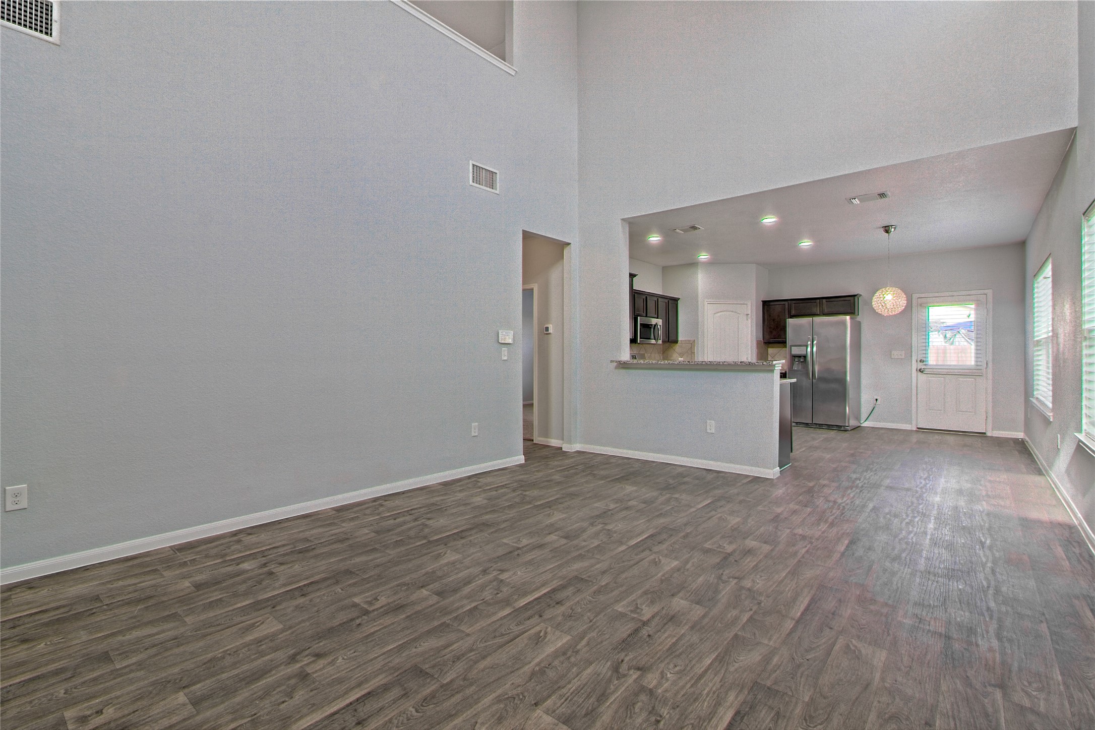 3408 Tilmon Ln. Austin, TX 78725 - Photo 8 of 35 Unfurnished living room featuring dark wood-style flooring, recessed lighting, and a high ceiling