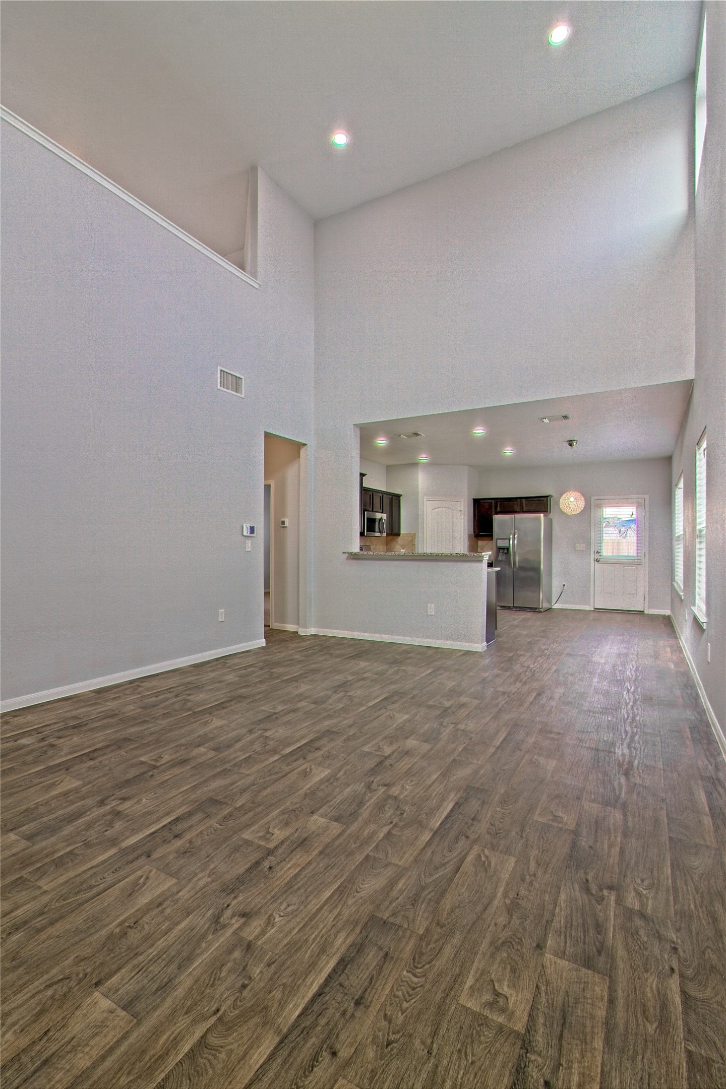 3408 Tilmon Ln. Austin, TX 78725 - Photo 10 of 35 Unfurnished living room with a high ceiling, dark wood finished floors, and recessed lighting
