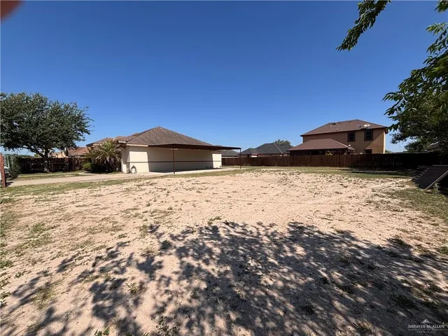 a backyard of a house with large trees and a wooden fence