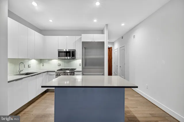 a large kitchen with stainless steel appliances granite countertop a refrigerator a stove and a sink