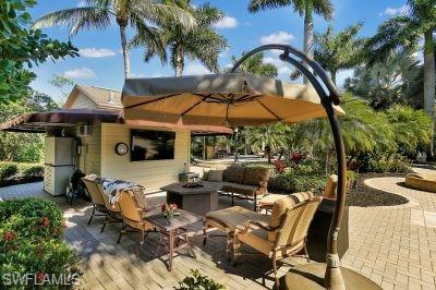 4991 Coach Lane Naples, FL 34114 - Photo 4 of 8 a patio with a table and chairs under an umbrella